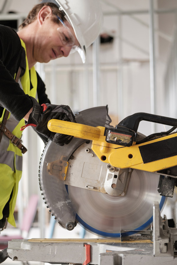 Carpenter cutting material with a miter saw on a Long Island build